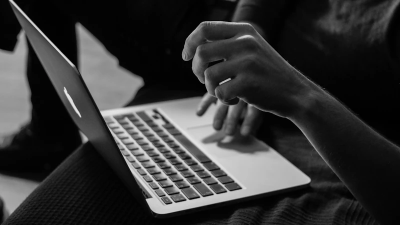 grayscale photo of person using MacBook