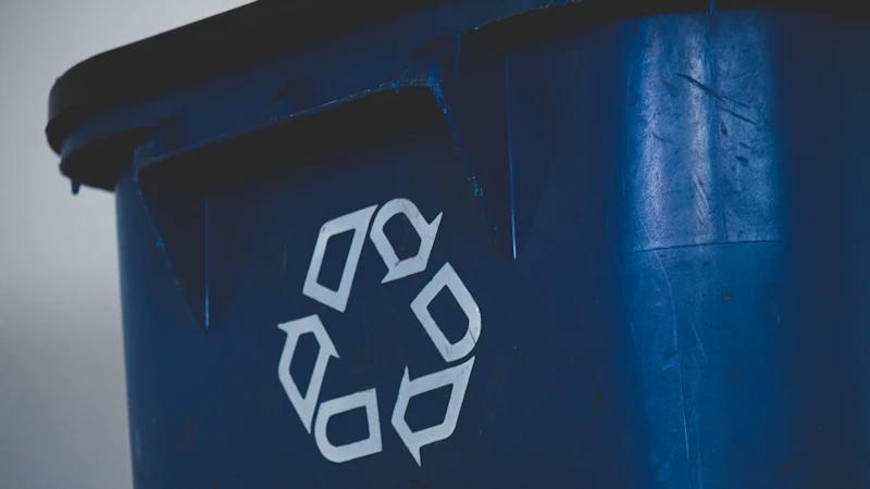A white recycling symbol on the side of a blue plastic bin