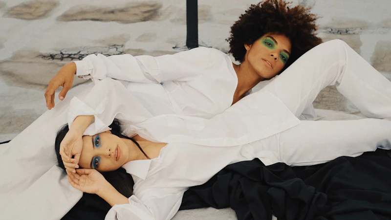 two women laying down wearing white dress shirts