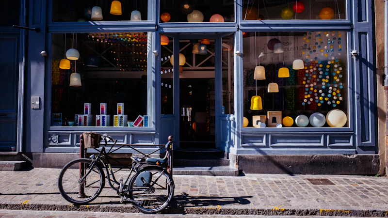 A bicycle parked on a cobblestone sidewalk in front of a lamp shop