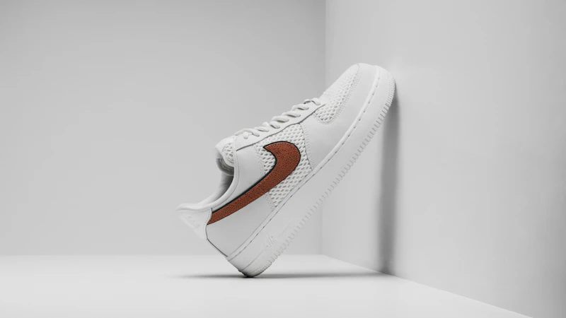 a white sneaker with a brown stripe on the side