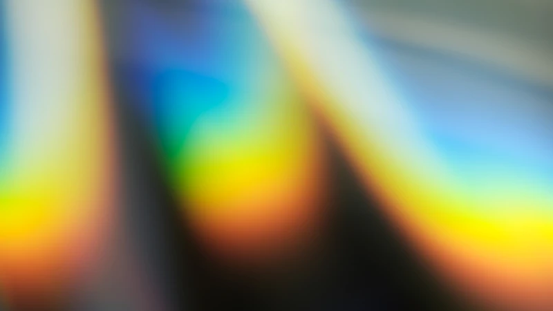 A soft abstract blur of rainbow colors including yellow, orange, and blue