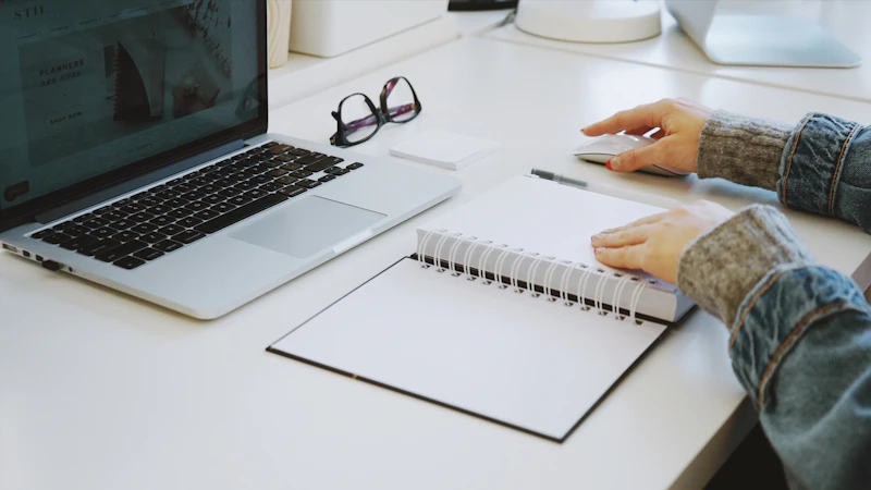 person touching white spiral notebook