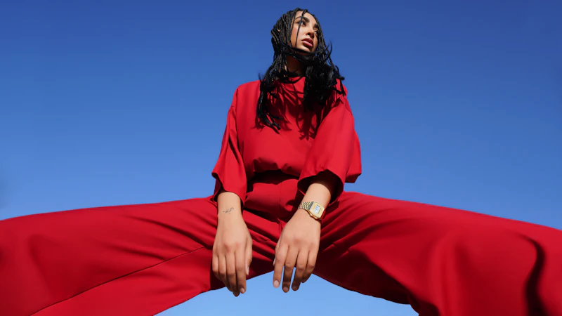 A woman with braided hair in a red outfit against a clear blue sky