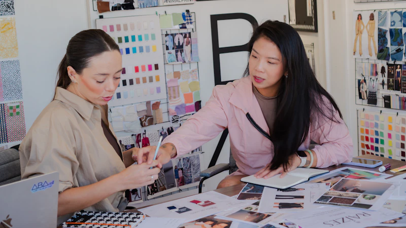 Two women collaborating at a desk with fabric swatches