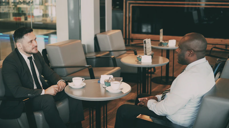 Two men in suits talking at a cafe