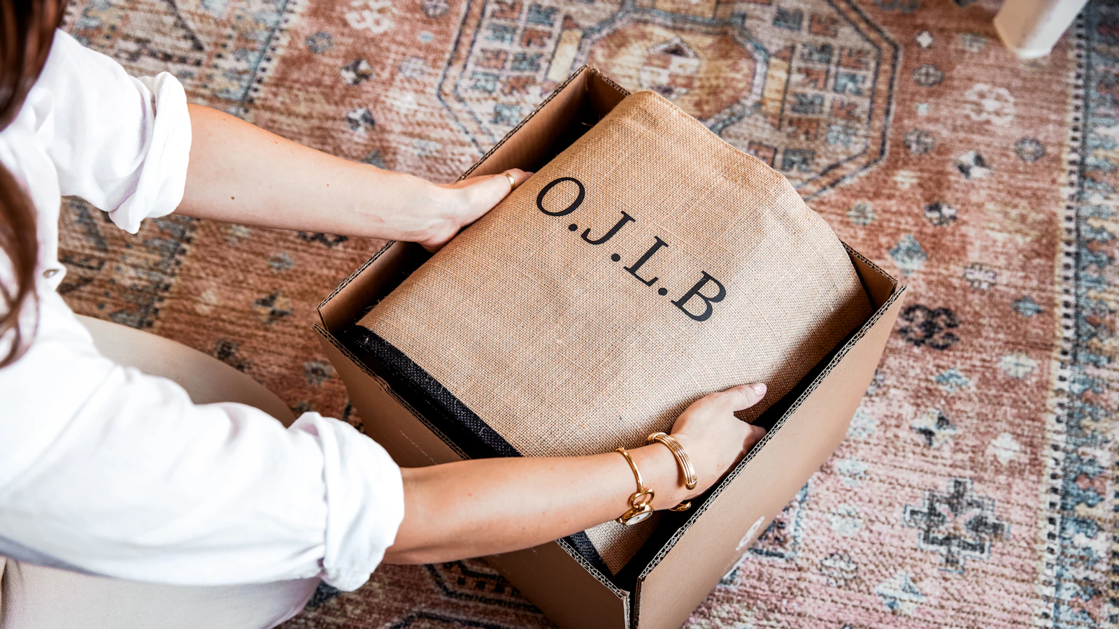Hands opening a box with o.j.l.b. branding