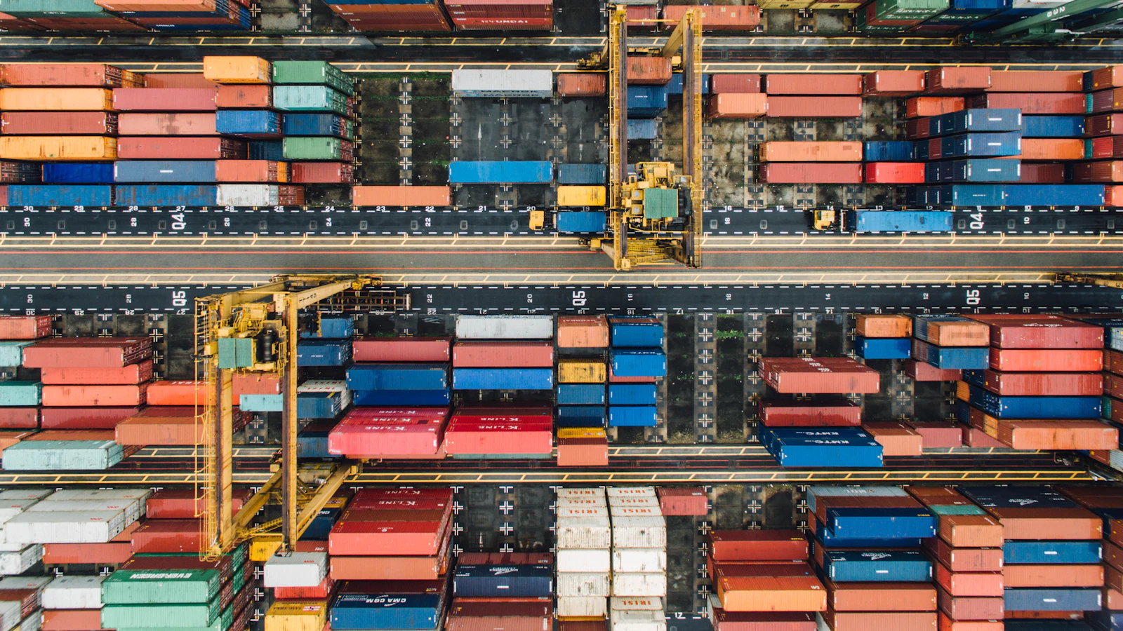 An aerial view of colorful shipping containers stacked in a busy industrial port