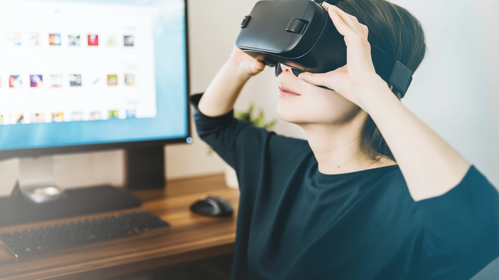 woman using black VR headset beside computer