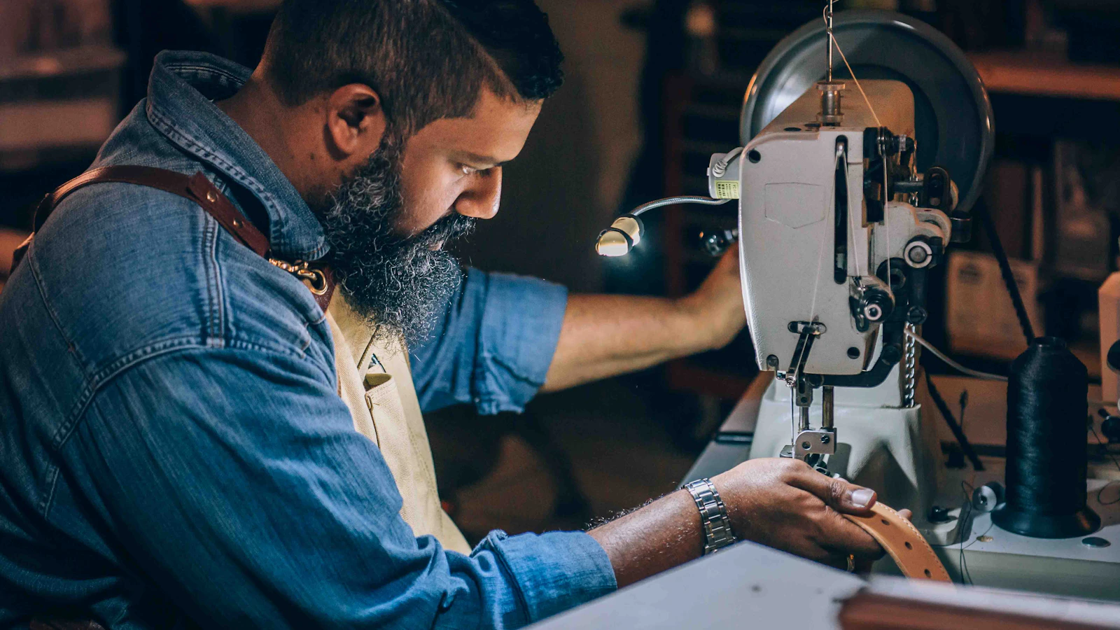 man sewing brown belt