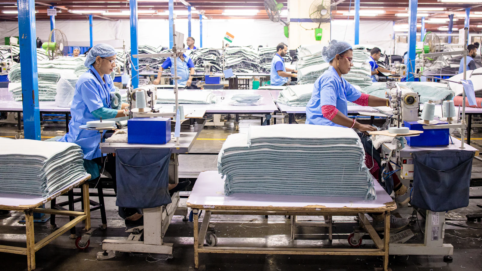 Workers sew textiles in a large factory setting