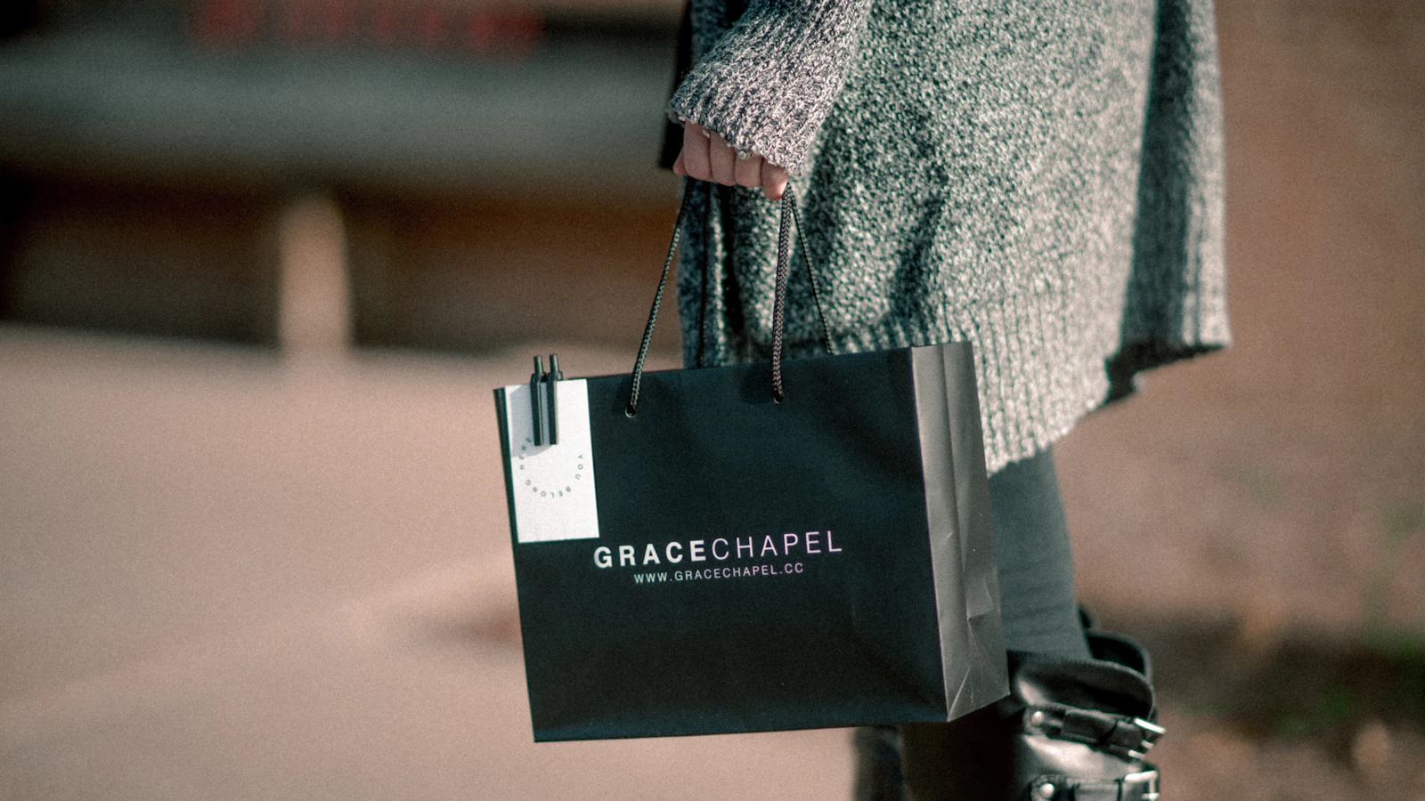 woman holding black paper tote bag