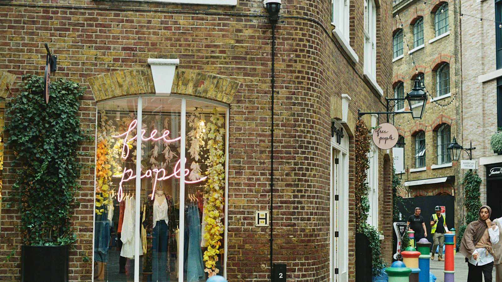 a woman walking down a street past a store front